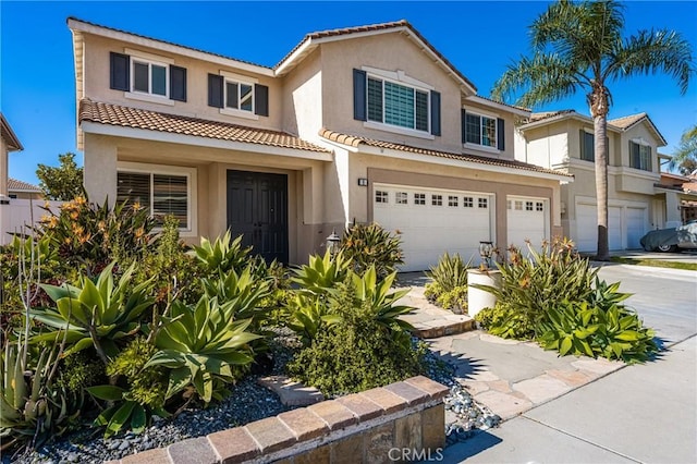 view of front of house featuring a garage, driveway, a tiled roof, and stucco siding