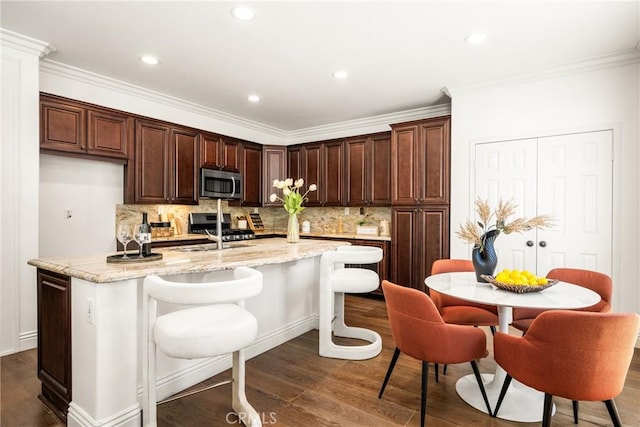 kitchen with dark wood-style flooring, a center island with sink, backsplash, appliances with stainless steel finishes, and a sink