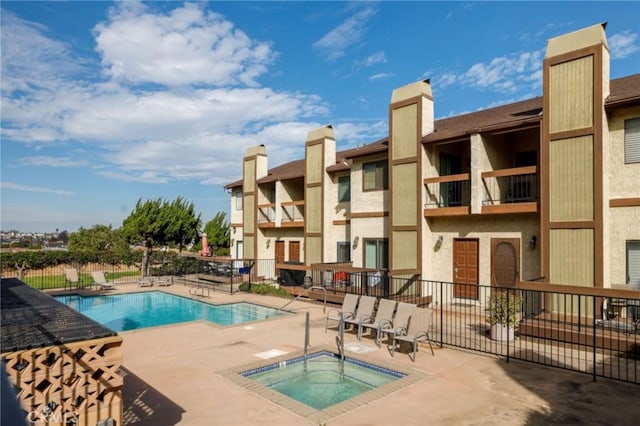 pool with a patio area, a hot tub, and fence