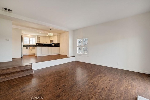 unfurnished living room featuring dark wood finished floors, visible vents, and baseboards