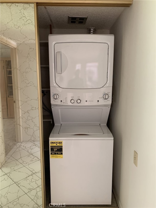 laundry room featuring stacked washer and dryer, visible vents, and a textured ceiling