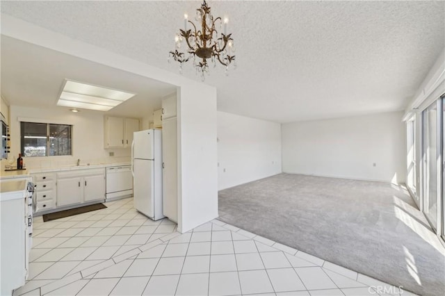 kitchen featuring light colored carpet, light countertops, open floor plan, white appliances, and an inviting chandelier
