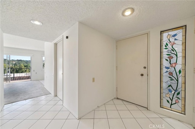 foyer with a textured ceiling and light tile patterned floors