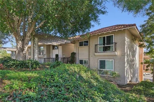 back of house featuring a pergola, stucco siding, and a tiled roof