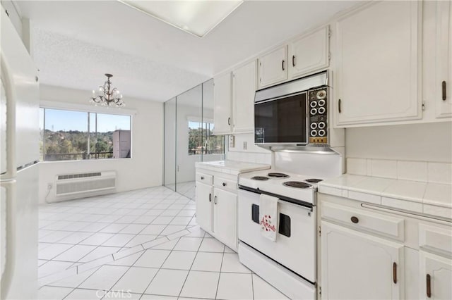 kitchen featuring a wall mounted AC, white appliances, tile countertops, white cabinets, and a notable chandelier