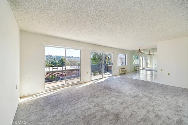 unfurnished living room featuring carpet flooring, a notable chandelier, and a textured ceiling