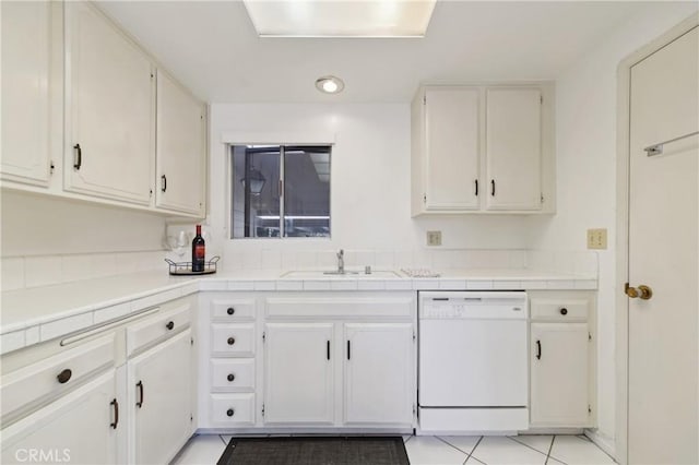 kitchen with dishwasher, white cabinets, a sink, and tile countertops