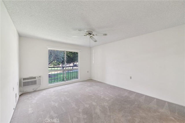 empty room with a wall mounted AC, carpet, a textured ceiling, and ceiling fan