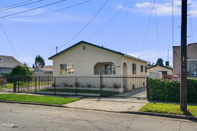 bungalow featuring a fenced front yard, a gate, and stucco siding