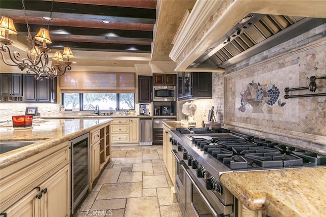 kitchen with stone tile floors, appliances with stainless steel finishes, light stone countertops, cream cabinetry, and premium range hood