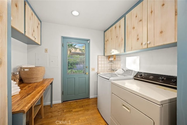 laundry area featuring cabinet space, light wood-style floors, and independent washer and dryer