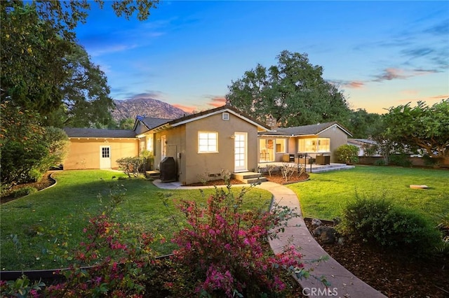 rear view of property featuring a yard and stucco siding