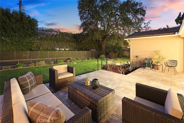 patio terrace at dusk with an outdoor hangout area, a lawn, and a fenced backyard