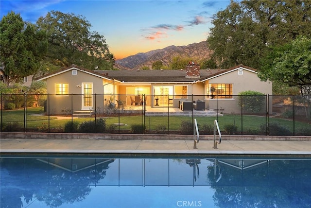 back of property featuring fence, a mountain view, and stucco siding