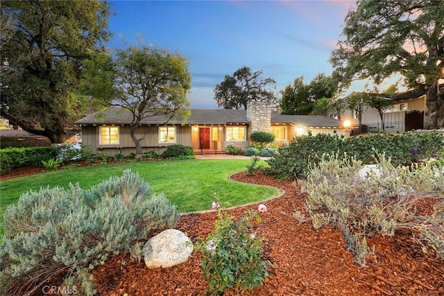 ranch-style house featuring a lawn, a chimney, and fence