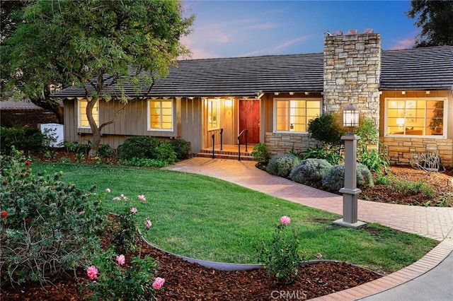 single story home featuring stone siding, a chimney, and a front yard