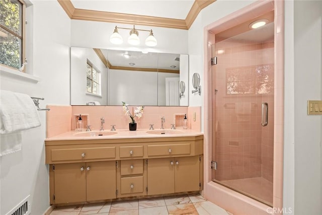 full bathroom with marble finish floor, a stall shower, a sink, and crown molding