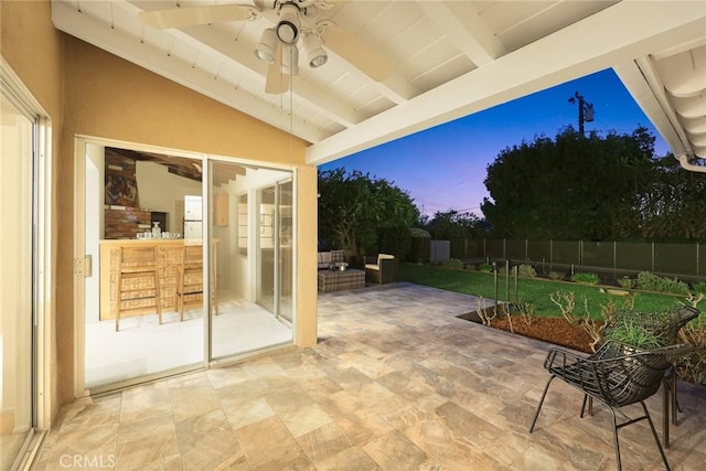 patio terrace at dusk featuring fence and a ceiling fan