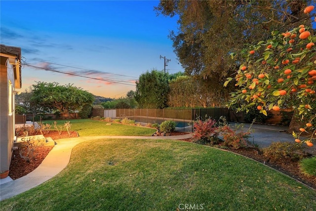 yard at dusk featuring a fenced backyard