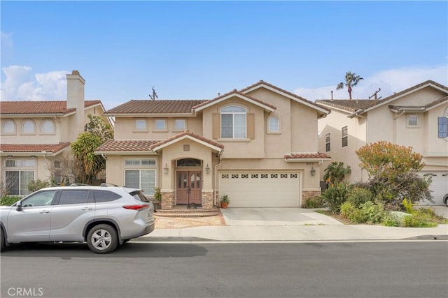 view of front of home with driveway, stone siding, a tile roof, and stucco siding