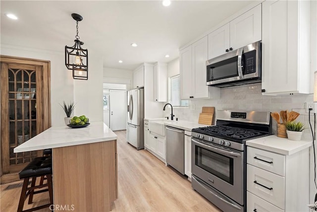 kitchen with light stone counters, tasteful backsplash, hanging light fixtures, appliances with stainless steel finishes, and white cabinetry