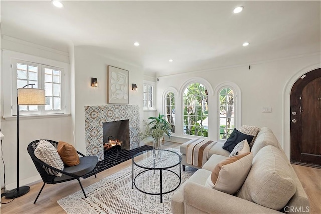 living room with arched walkways, a fireplace with flush hearth, light wood-style flooring, and recessed lighting