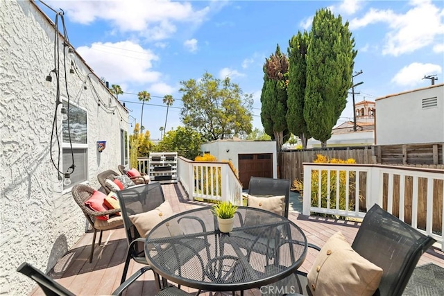 wooden terrace with a storage shed, a fenced backyard, an outdoor structure, and outdoor dining space