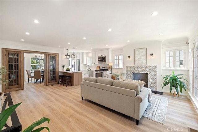 living room with baseboards, light wood finished floors, a tile fireplace, and recessed lighting