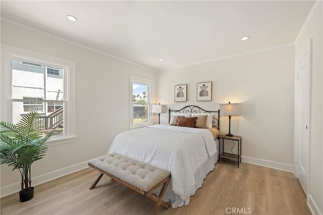 bedroom with ornamental molding, light wood finished floors, and baseboards