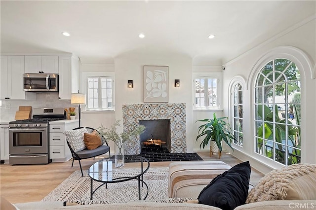 living area featuring light wood finished floors, a fireplace with flush hearth, a wealth of natural light, and recessed lighting