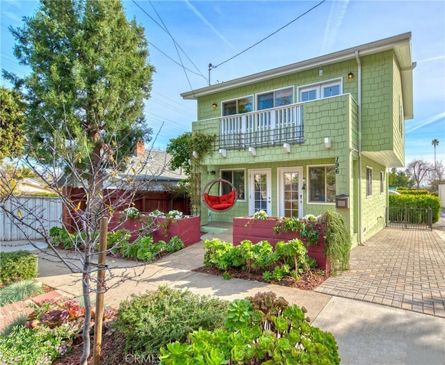 front of property featuring a balcony and fence