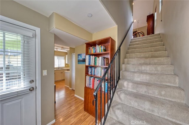 staircase featuring wood finished floors and baseboards