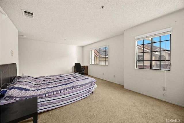 bedroom with carpet floors, visible vents, and a textured ceiling