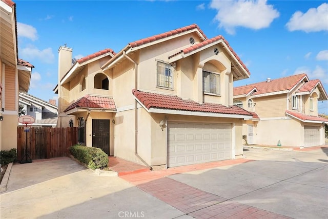 mediterranean / spanish home with driveway, a tile roof, a chimney, fence, and stucco siding