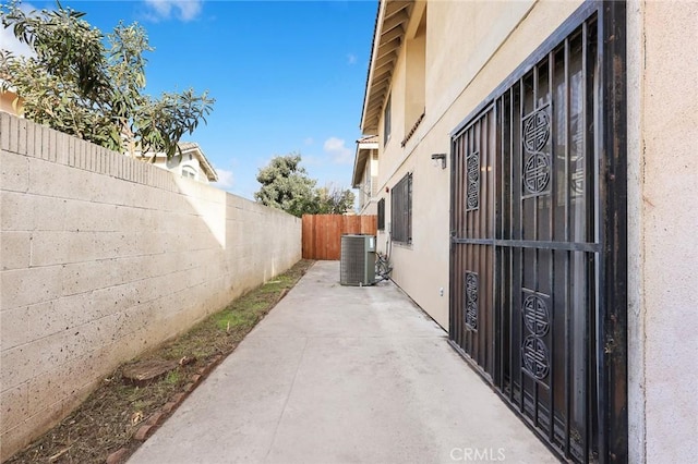 view of side of property with a fenced backyard, a patio, cooling unit, and stucco siding