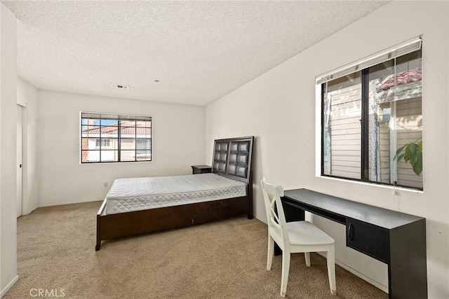 bedroom featuring carpet, visible vents, and a textured ceiling