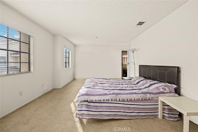 bedroom featuring carpet, visible vents, and a textured ceiling