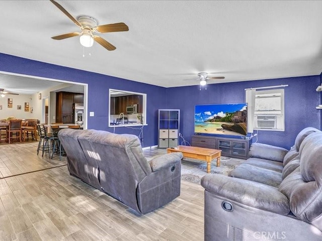 living room with cooling unit, ceiling fan, and light wood finished floors