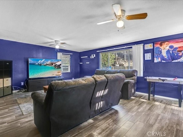 home theater room with a ceiling fan, a textured ceiling, baseboards, and wood finished floors