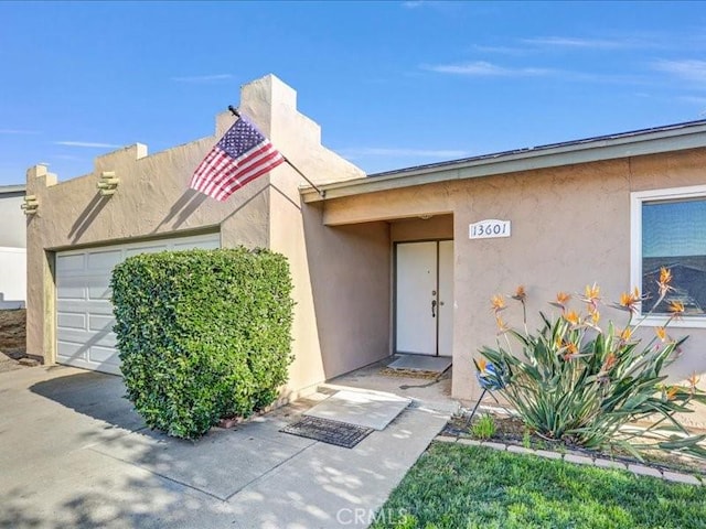 entrance to property with driveway, an attached garage, and stucco siding