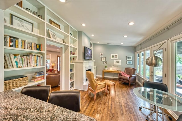 living area with recessed lighting, a fireplace, wood finished floors, baseboards, and french doors