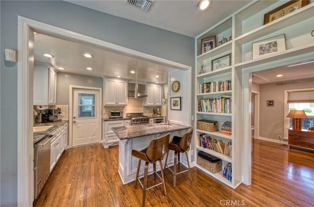 kitchen featuring a breakfast bar, stainless steel appliances, visible vents, stone countertops, and white cabinets