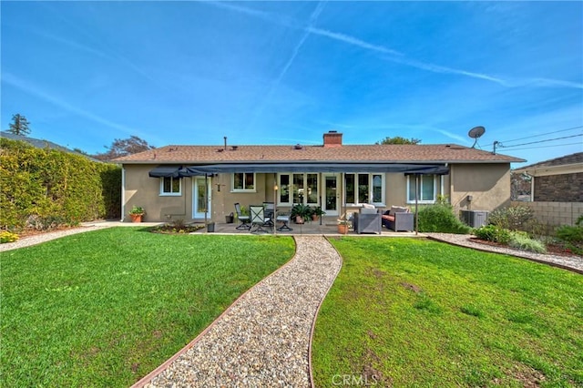 back of house featuring a lawn, a patio, a chimney, fence, and stucco siding