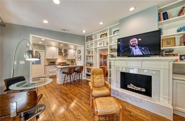 living area with light wood-style flooring, a high end fireplace, visible vents, and recessed lighting