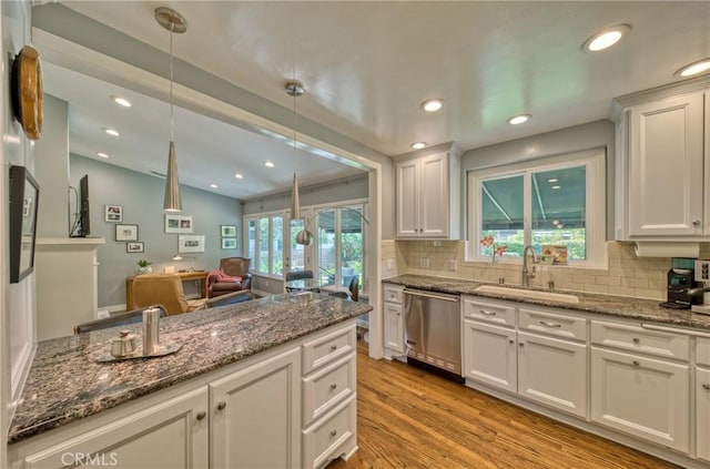 kitchen with decorative light fixtures, light wood-type flooring, stainless steel dishwasher, white cabinetry, and a sink