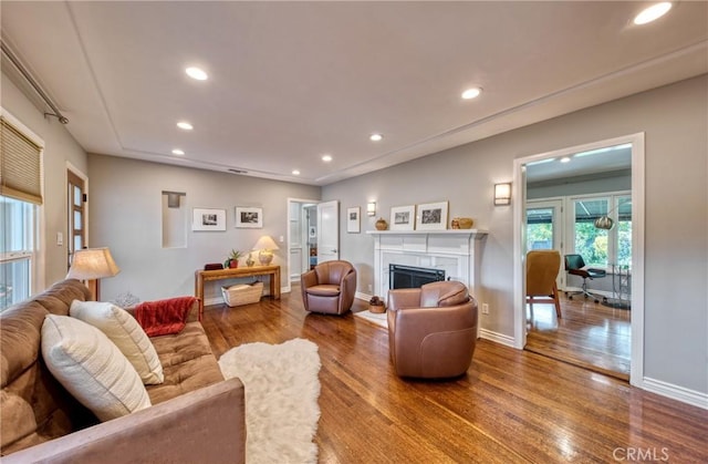 living area with recessed lighting, a fireplace, baseboards, and wood finished floors