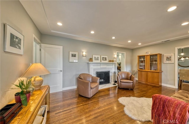 living room featuring dark wood-type flooring, a fireplace, and recessed lighting