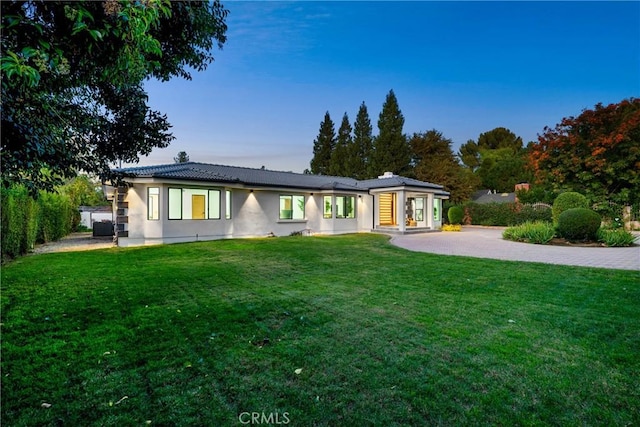 rear view of property featuring a patio area, fence, a lawn, and stucco siding