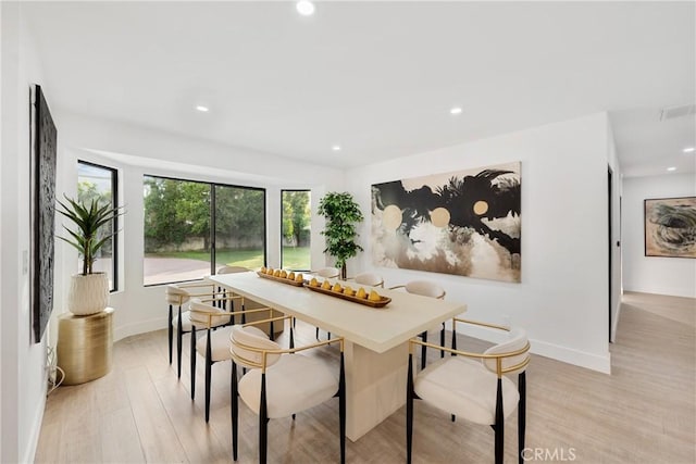 dining space featuring baseboards, light wood finished floors, and recessed lighting