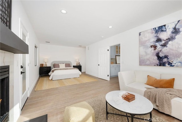 bedroom featuring recessed lighting, a fireplace, baseboards, and wood finished floors